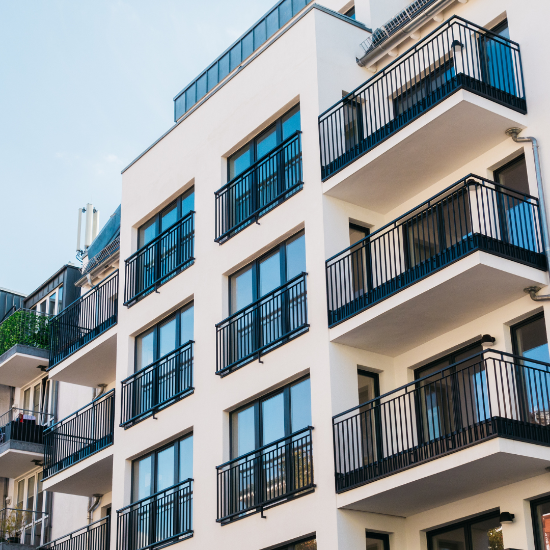 A white apartment building with a balcony in a suburban setting.