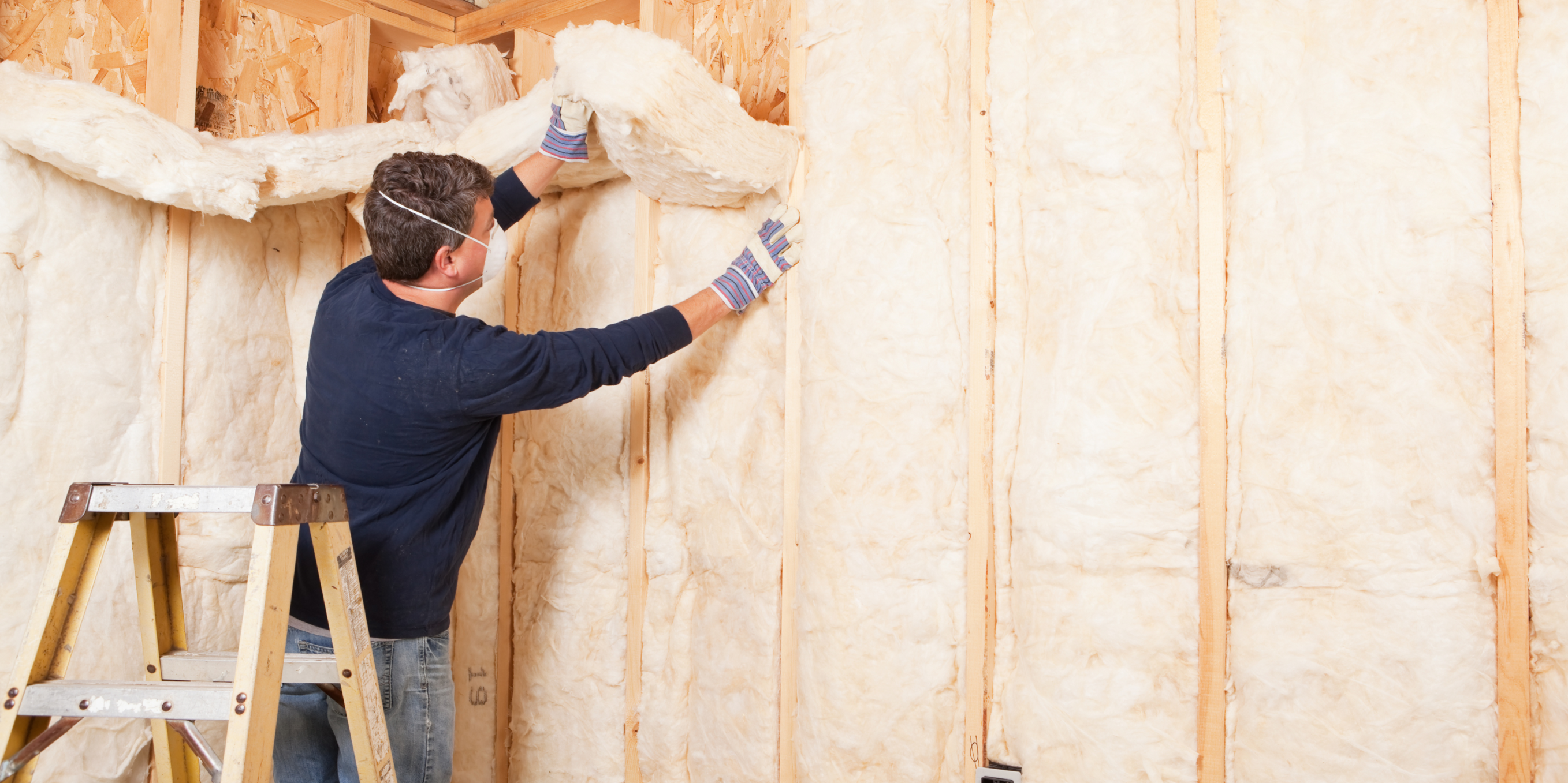 A man wearing protective clothing and using insulation materials to insulate a roof, ensuring energy efficiency and temperature control in a home